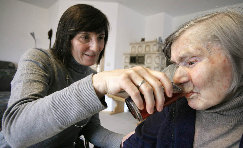 Klara Müller gibt ihrer demenzkranken Mutter Maria Maier zu trinken.