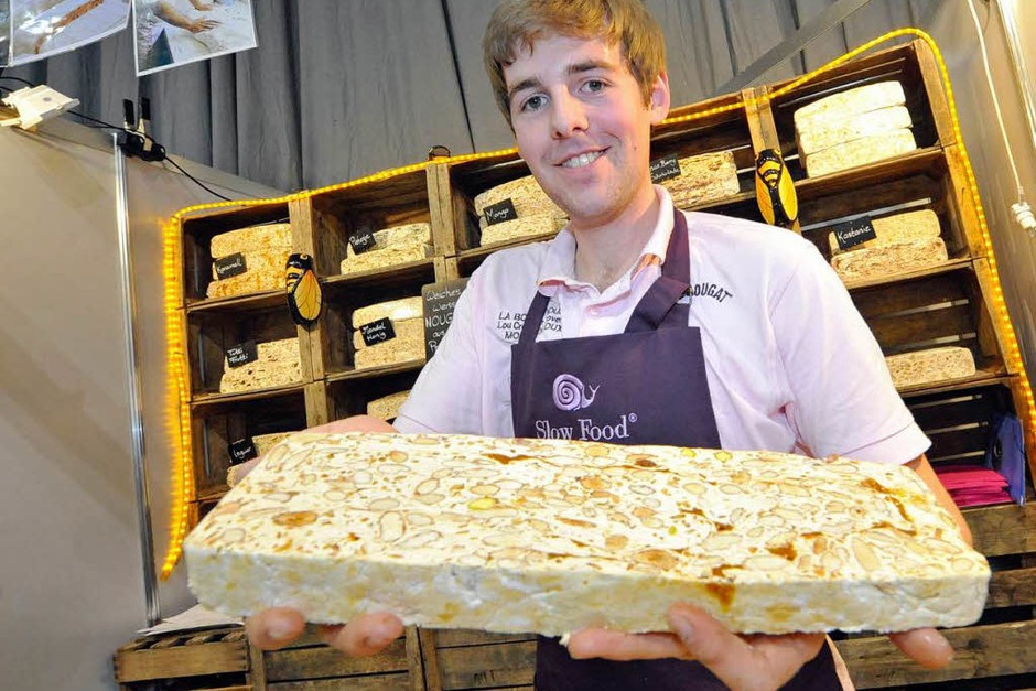 Was Andrew Williamson hier in die Kamera hält, ist keine marmorierte Steinplatte sondern butterweiches weißes Nougat aus der Provence. Eine Süßigkeit aus Eiweiß, Zucker, Pistazien und, besonders wichtig, Lavendelhonig. „Man hat das Gefühl, man beißt in die Provence“, sagt Williamsons Kollegin. Auszuprobieren am Slow-Food-Stand in Halle zwei. (Foto: Michael Bamberger) Was Andrew Williamson hier in die Kamera hält, ist keine marmorierte Steinplatte sondern butterweiches weißes Nougat aus der Provence. Eine Süßigkeit aus Eiweiß, Zucker, Pistazien und, besonders wichtig, Lavendelhonig. „Man hat das Gefühl, man beißt in die Provence“, sagt Williamsons Kollegin. Auszuprobieren am Slow-Food-Stand in Halle zwei. (Foto: Michael Bamberger)