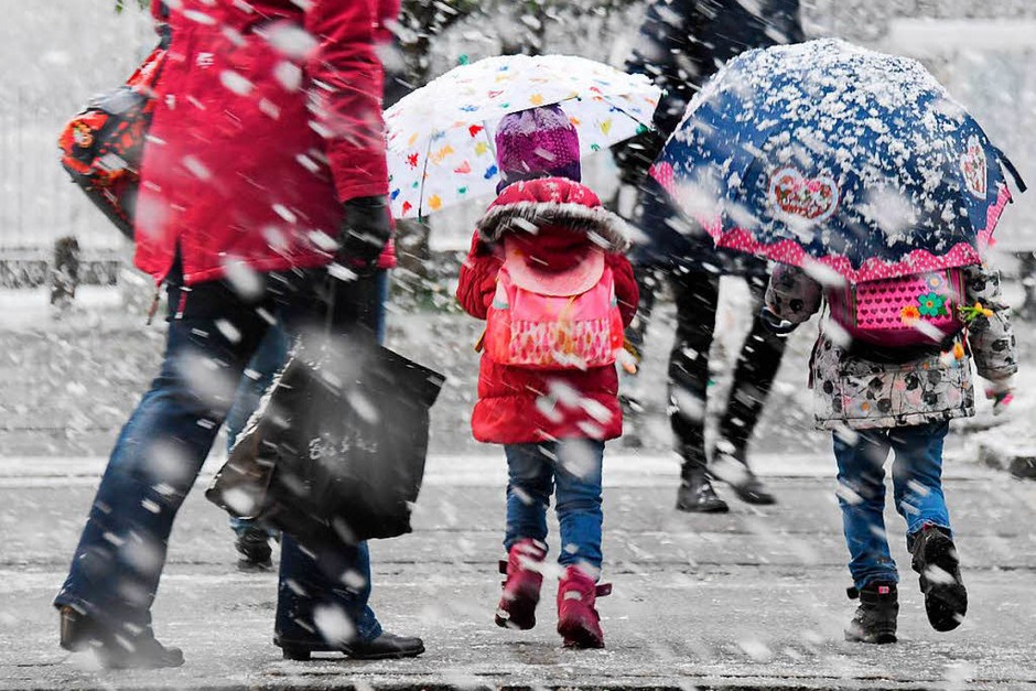Zwei Kinder mit Regenschirmen gehen am Dienstag in München bei Schneefall über eine Straße. (Foto: dpa) Zwei Kinder mit Regenschirmen gehen am Dienstag in München bei Schneefall über eine Straße. (Foto: dpa)