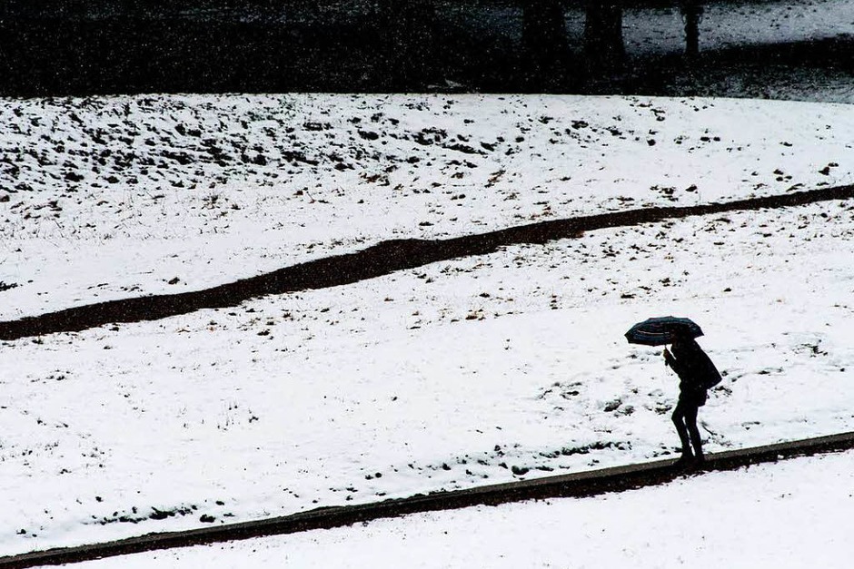 Eine Frau läuft am Ostermontag auf dem Feldberg im Schwarzwald mit dem Regenschirm an verschneiten Wiesen vorbei. (Foto: dpa) Eine Frau läuft am Ostermontag auf dem Feldberg im Schwarzwald mit dem Regenschirm an verschneiten Wiesen vorbei. (Foto: dpa)