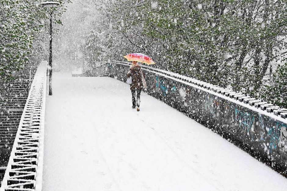 Eine Frau geht am Dienstag in München bei Schneefall über eine verschneite Fußgängerbrücke. (Foto: dpa) Eine Frau geht am Dienstag in München bei Schneefall über eine verschneite Fußgängerbrücke. (Foto: dpa)