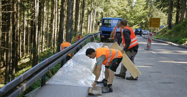 Damit der Sichtbeton an der Bundesstra...Bauarbeiter mit einer Folie vor Regen. 