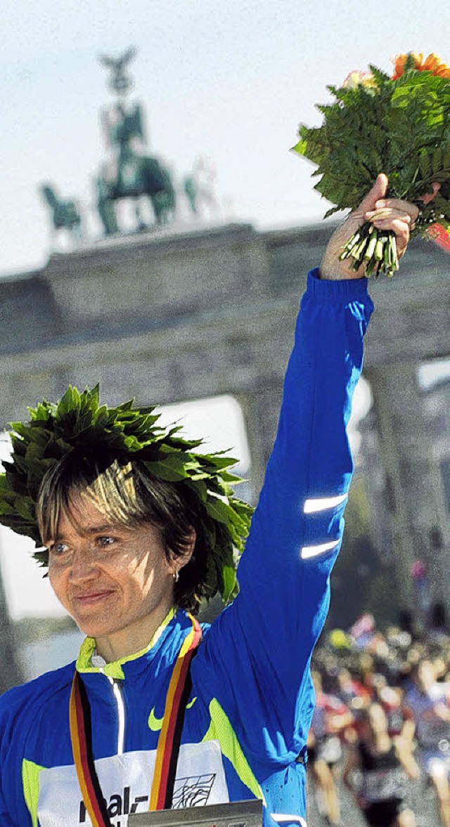 Irina Mikitenko mit Lorbeerkranz und Blumen in der Nhe des Brandenburger Tores  | Foto: dpa