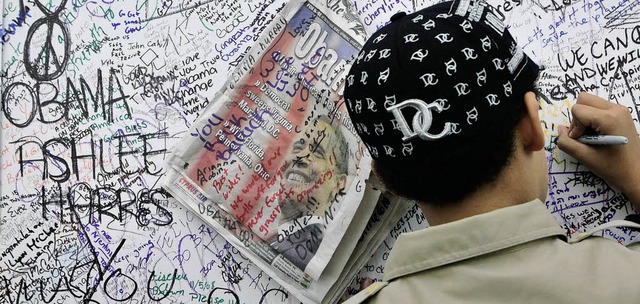 Ein Junge schreibt in Washington  auf ...-Wand eine Botschaft an Barack Obama.   | Foto: afp