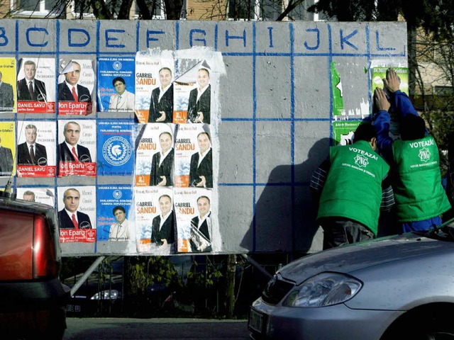 Wahlkampfhelfer kleben Plakate in Rumniens Hauptstadt Bukarest.   | Foto: DPA