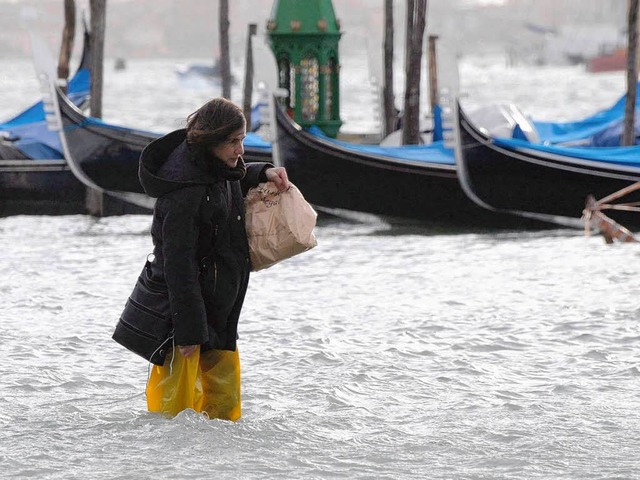 Mit Plastiktten um die Beine luft di... die berfluteten Straen von Venedig.  | Foto: dpa