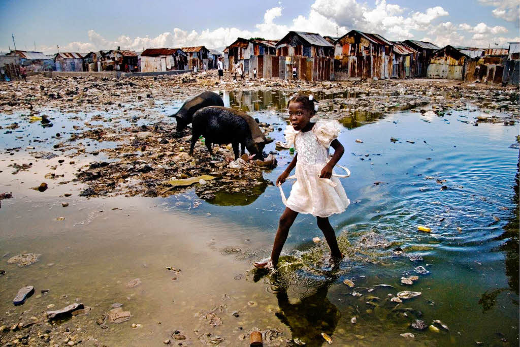 Das  Unicef-Foto des Jahres 2008  von Alice Smeets zeigt ein Mdchen, das durch Schmutzwasser im grten Slum von Port-au-Prince auf Haiti watet.