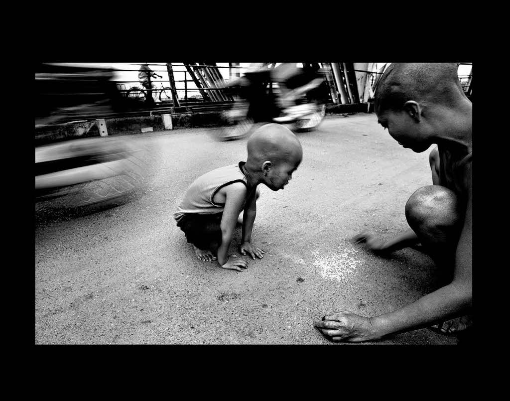 PhaMui und ihr fnfjhriger Sohn Pha sammeln von einer Strae in Hanoi, Vietnam alte Reiskrner auf.