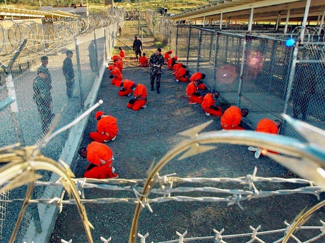 In Overalls gekleidet sitzen Hftlinge...inesttzpunkt Guantnamo Bay auf Kuba.  | Foto: dpa