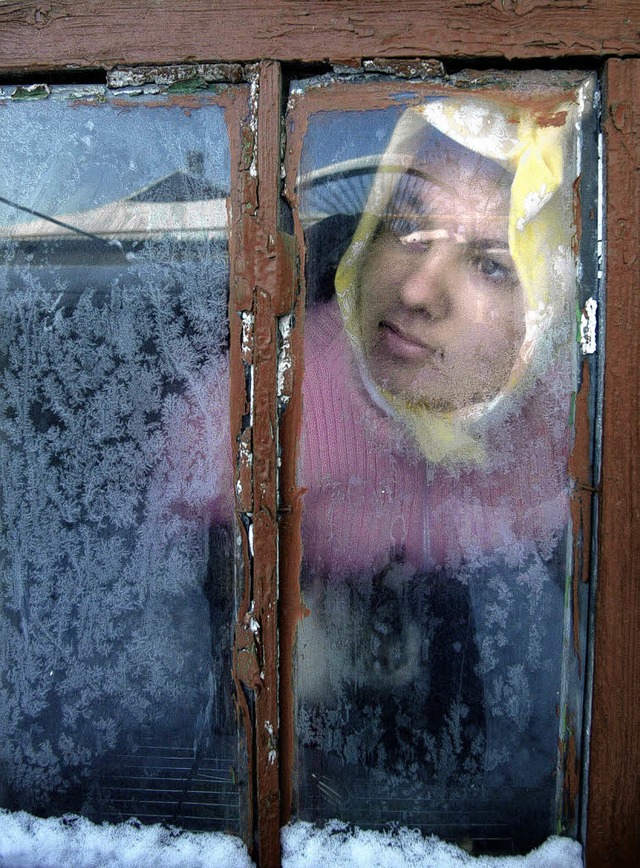 Hinter Eisblumen sitzt ein ukrainisches Mdchen am Fenster.  | Foto: AFP