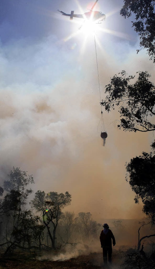 Ein Hubschrauber wirft eine Wasserbombe ber einem Feuer ab.   | Foto: AFP