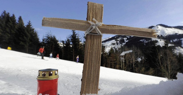 Ein Kreuz und eine Kerze stehen auf de...ren Skifahrerin zusammengeprallt ist.   | Foto: ddp