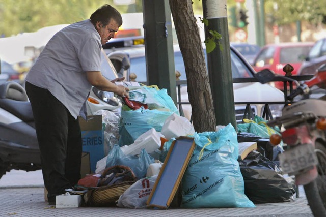 Ein Obdachloser in Athen whlt in Abfalltten nach Essbarem.  | Foto: afp