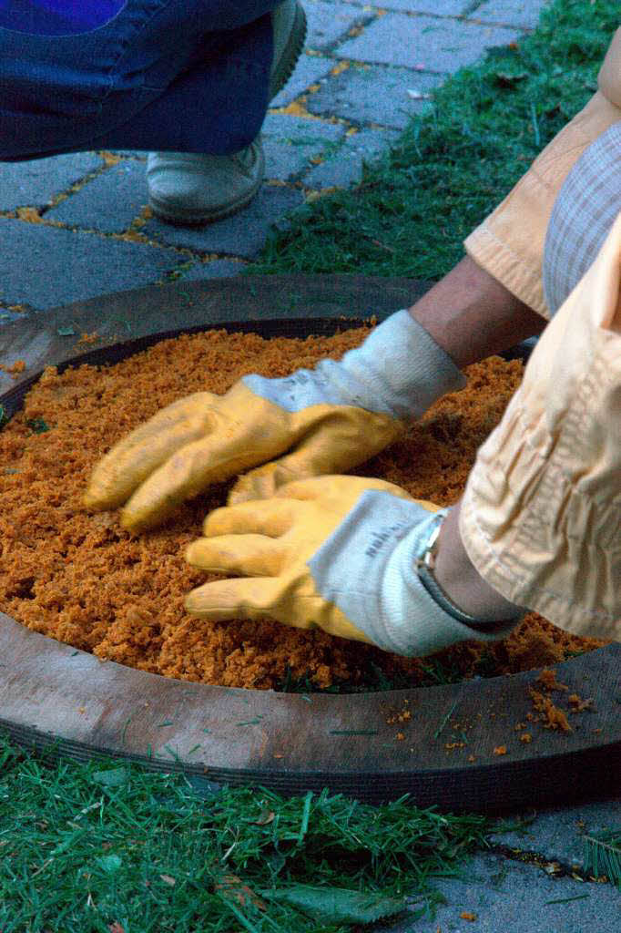 In vorgefertigten Holzrahmen werden gefärbte Sägespäne verteilt. Die Rahmen werden sofort wieder entfernt. In vorgefertigten Holzrahmen werden gefärbte Sägespäne verteilt. Die Rahmen werden sofort wieder entfernt.