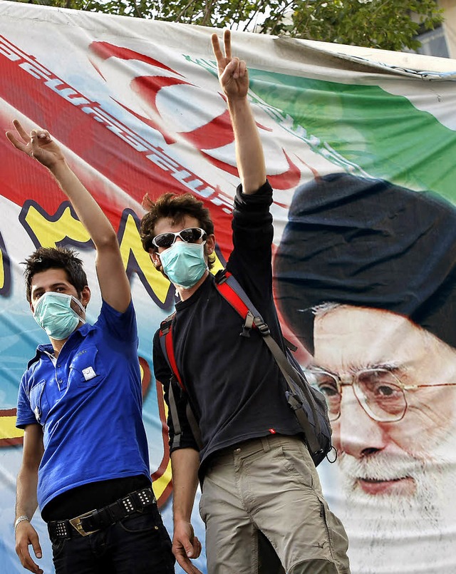 Anhnger Mussawis vor einem Plakat mit Ali Khamenei  | Foto: afp