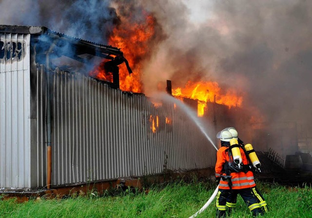 Ein Feuerwehrmann versucht am Mittwoch... eine brennende Lagerhalle zu lschen.  | Foto: dpa
