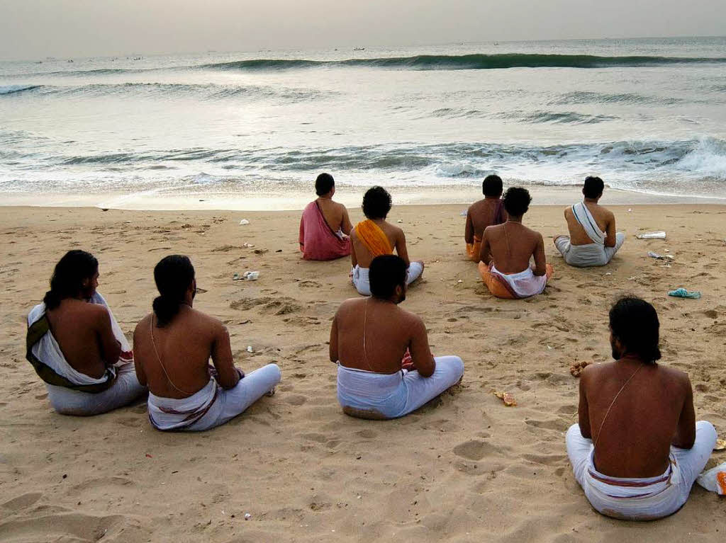Inder beten am Strand von Chennai in Indien zur Sonne.