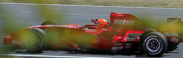 Zwischen Bumen hindurchfotografiert: ...chumacher im zwei Jahre alten Ferrari   | Foto: dpa