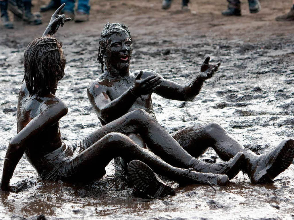 Heavy Metal-Fans sitzen halb nackt im Schlamm.