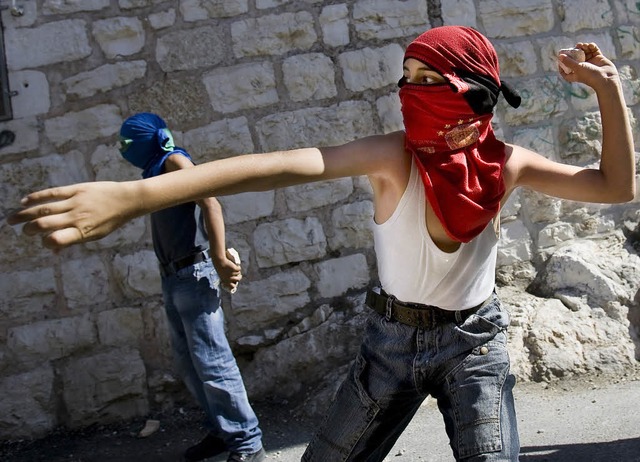 Junge maskierte Palstinenser werfen i...lem Steine auf israelische Polizisten.  | Foto: afp