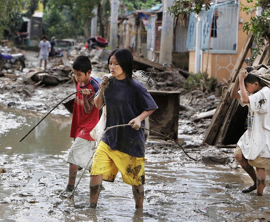 Diese Philippinos retten das Nötigste aus ihren Häusern.  | Foto: dpa