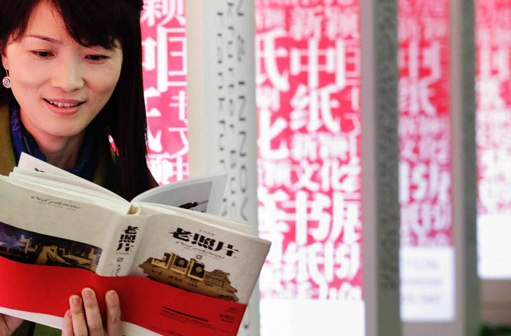 Eine Mitarbeiterin liest auf der Buchmesse in Frankfurt/Main an einem chinesischen Stand in einem Buch. Eine Mitarbeiterin liest auf der Buchmesse in Frankfurt/Main an einem chinesischen Stand in einem Buch.