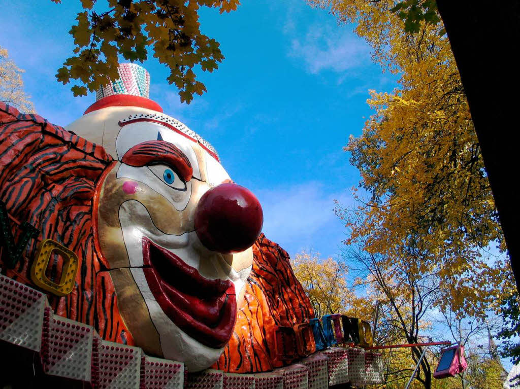 Eines der Fahrgeschfte wirbt mit einem riesigen Clownsgesicht.