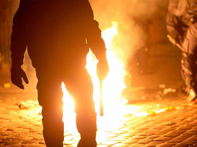 Ein Polizist in Hamburg neben einer vo...tremisten in Brand gesetzten Barrikade  | Foto: dpa