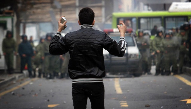 Mit Steinen bewaffnet: Ein Demonstrant...einer Gruppe von Polizisten gegenber.  | Foto: afp