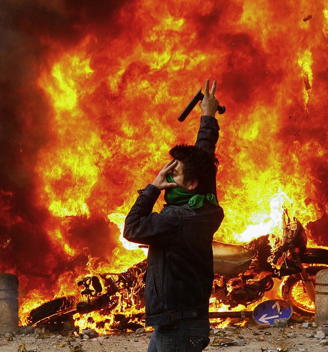 Ein Demonstrant steht   neben einem brennenden Polizeimotorrad.  | Foto: afp