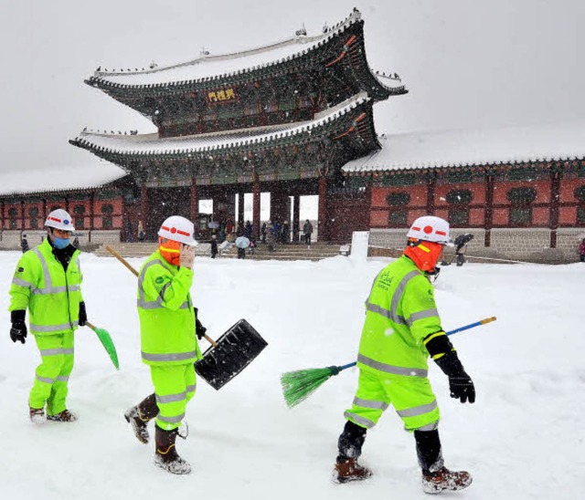 Mit Schneeschaufeln und Besen ausgers...u einem Palast in Seoul freizumachen.   | Foto: AFP