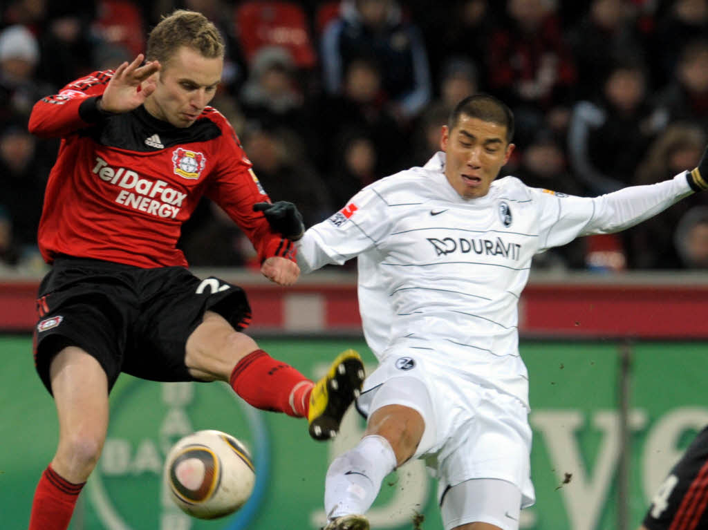 Der Leverkusener Michal Kadlec und der Freiburger Du-Ri Cha versuchen den Ball zu spielen.