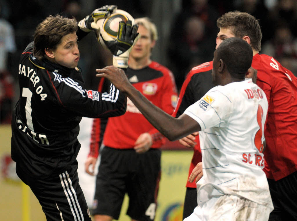 Der Leverkusener Torwart Rene Adler (l) und der Freiburger Mohamadou Idrissou versuchen den Ball zu spielen.