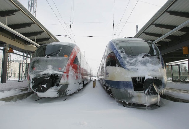 Zwei vereiste Zge stehen am Hauptbahnhof in Rostock auf verschneiten Gleisen.  | Foto: ddp