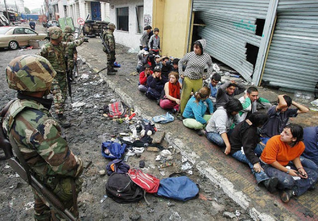 Soldaten bewachen  in der chilenischen...alcahuano eine Gruppe von Plnderern.   | Foto: dpa