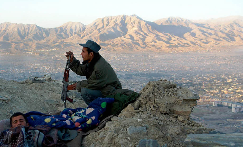 Polizisten bewachen die Berge vor Taliban bergriffen. Im Hintergrund geht ber Kabul die Sonne auf.