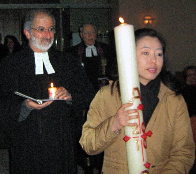Yunduk Lee mit der Osterkerze und Pfarrer Eberhard Deusch auf dem Weg zum Altar   | Foto: freyer