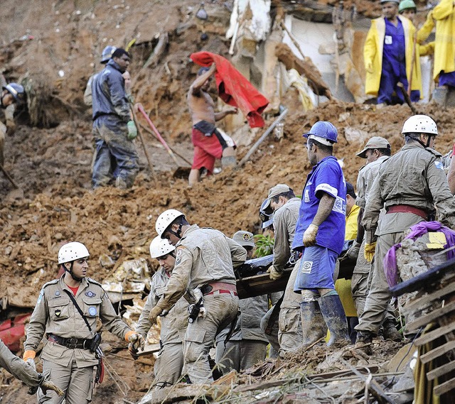 Helfer tragen ein Opfer aus den Trmmern das Armenviertels von Rio de Janeiro.   | Foto: AFP