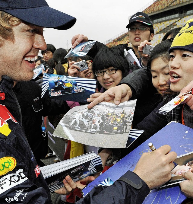 Autogramme von Sebastian Vettel (links...ei den chinesischen Fans hei begehrt.  | Foto: dpa