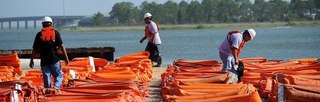 Letztes Mittel: Mnner bereiten schwimmfhige  lbarrieren vor   | Foto: AFP