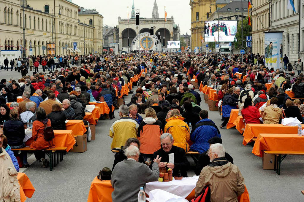 Besucher teilen am Freitag  am Odeonsplatz bei einer orthodoxen Vesper an einem gedeckten Tisch das Brot miteinander.