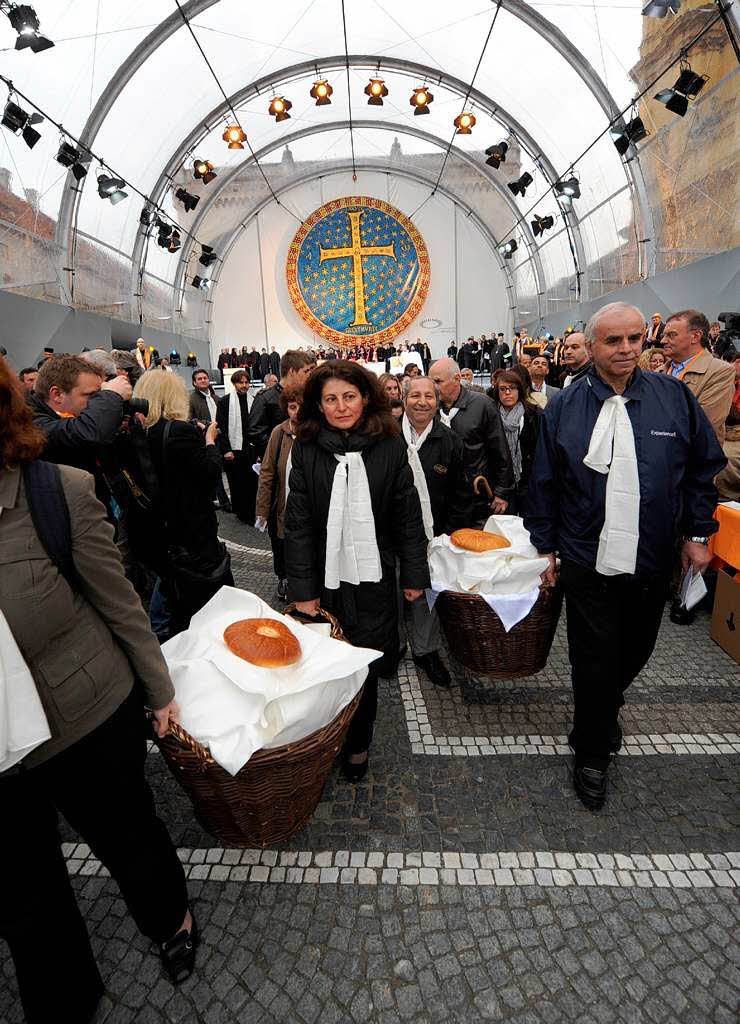 Besucher teilen am Freitag  am Odeonsplatz bei einer orthodoxen Vesper an einem gedeckten Tisch das Brot miteinander.