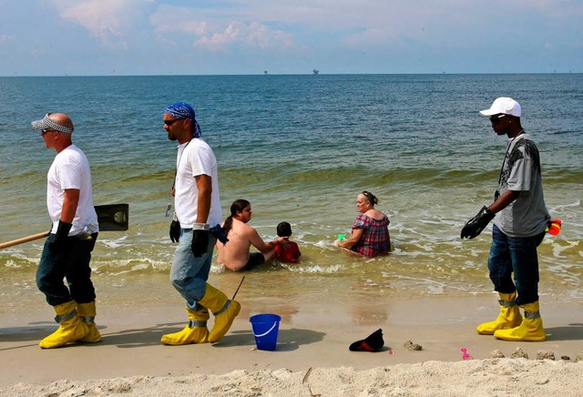 Whrend die einen noch baden, sind die... bereits groe lklumpen angeschwemmt.  | Foto: dpa