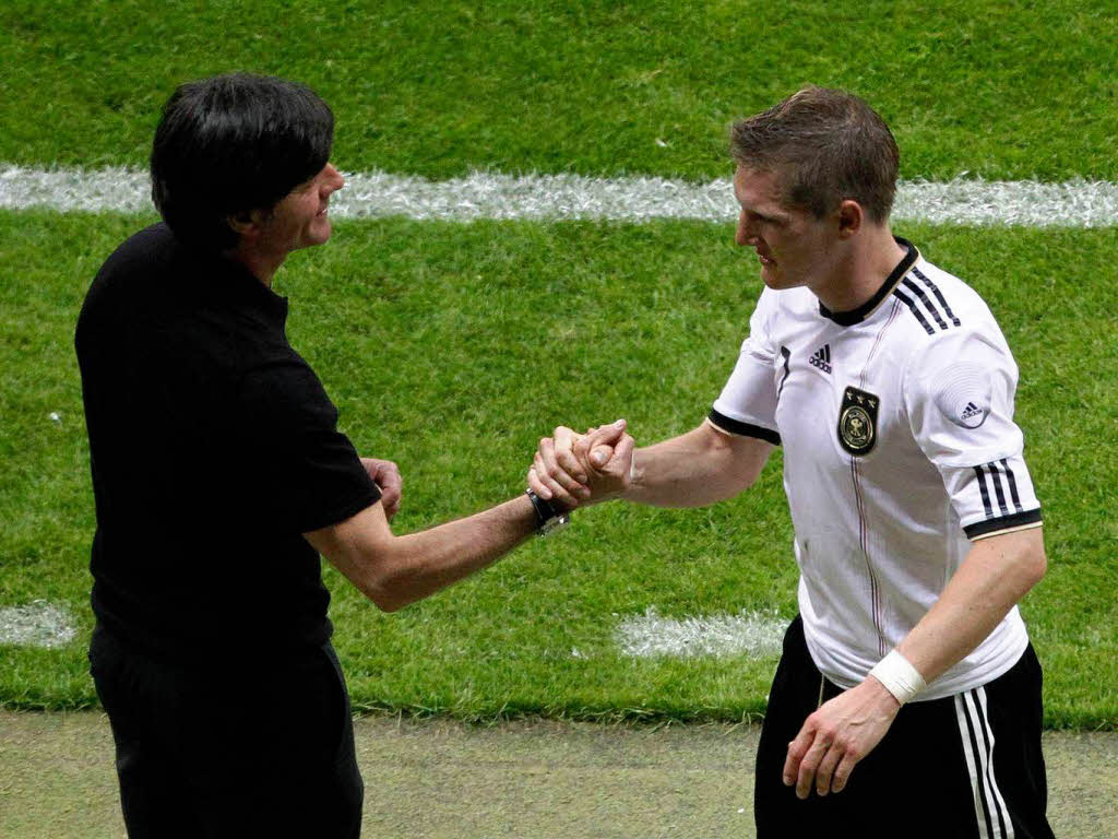 Bastian Schweinsteiger (r.) gibt Bundestrainer Joachim Loew nach seiner Auswechslung die Hand.