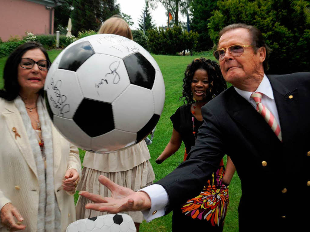 Pressekonferenz auf der Bhlerhhe: Schauspieler Sir Roger Moore wirft  einen Fuball in die Hhe.