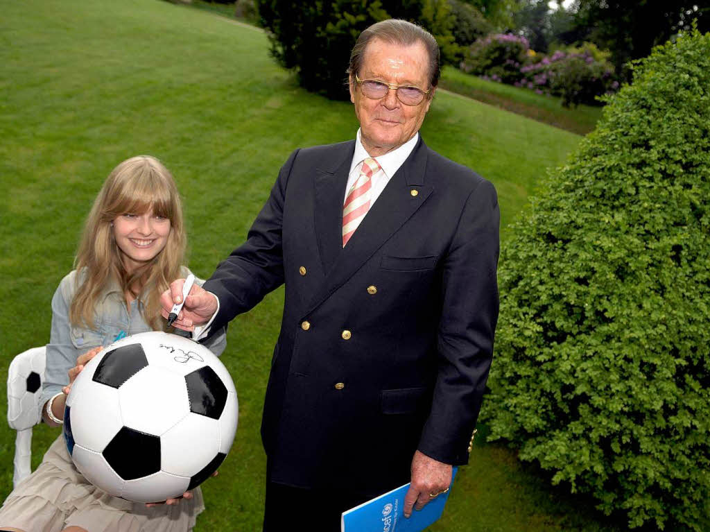 Pressekonferenz auf der Bhlerhhe:  Sir Roger Moore und Model  Julia Stegner