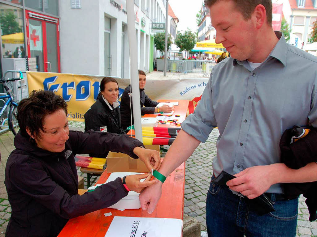 Public Viewing in Offenburg: Sandra Wenzel  legt Florian Buster das Eintrittsbndchen fr die WM-Arena auf dem Marktplatz um.