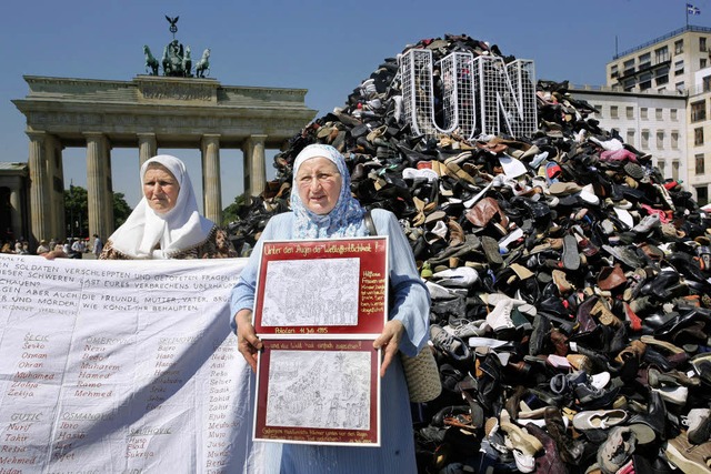 Zwei bosnische Frauen stehen am Sonnta...kers von Srebrenica aufgetrmt worden.  | Foto: dpa