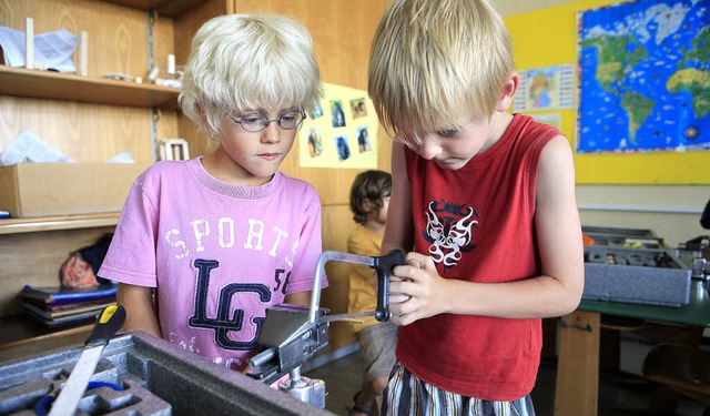 Paul und Noah sgen sich das fehlende Teilstck  am Schraubstock zurecht.  | Foto: christoph breithaupt