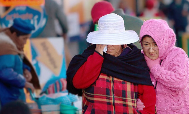 Zwei Frauen in Bolivien schtzen sich ...idung vor den frostigen Temperaturen.   | Foto: dpa